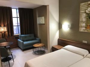 a hotel room with a bed and a chair at Pensión Iznájar Barcelona in Barcelona