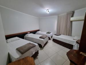 a hotel room with three beds and a window at Marion Pantanal Hotel in Várzea Grande
