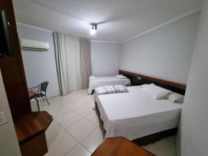 a hotel room with two beds and a chair at Marion Pantanal Hotel in Várzea Grande
