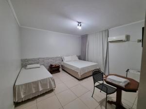 a bedroom with two beds and a desk and a chair at Marion Pantanal Hotel in Várzea Grande