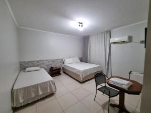 a room with two beds and a chair in it at Marion Pantanal Hotel in Várzea Grande