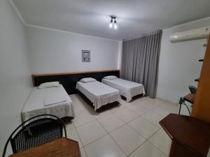 a hotel room with two beds and a table at Marion Pantanal Hotel in Várzea Grande