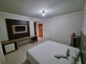 a bedroom with a bed and a desk and a television at Marion Pantanal Hotel in Várzea Grande