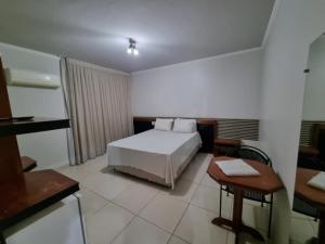 a bedroom with a white bed and a table and a tablektop at Marion Pantanal Hotel in Várzea Grande