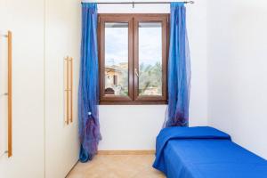 Un dormitorio con una cama azul y una ventana en [2 KM DAL MARE] Villetta relax con barbecue, en Palmadula