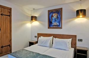 a bedroom with a bed with two lights on the wall at Aparthotel Dar Nowara Chaouen in Chefchaouene