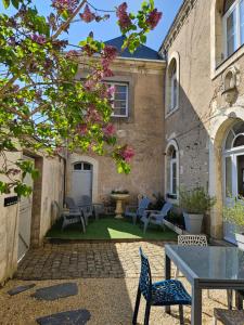un patio con sillas y una mesa frente a un edificio en Confidences Escale à Brissac, en Brissac-Quincé