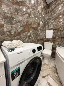 - un lave-linge dans la salle de bains pourvue de toilettes dans l'établissement Aportament in Abyroy Residence, à Atyraū
