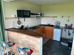a kitchen with a counter with a stove and a refrigerator at Maison charmante à Rivière-Salée avec piscine privée in Rivière-Salée