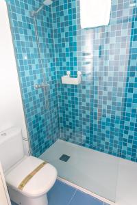 y baño de azulejos azules con aseo y ducha. en Casa Luz de Rajamanta - Terraza vistas a 1º línea y Parking, en Barbate