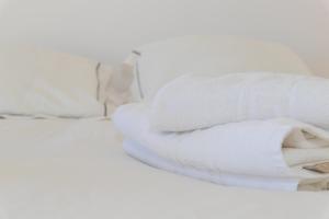 una pila de toallas blancas sentadas en una cama en Casa Luz de Rajamanta - Terraza vistas a 1º línea y Parking, en Barbate