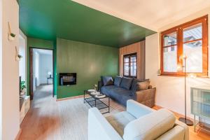 - un salon avec un canapé et un mur vert dans l'établissement La FORGE Appartement chaleureux et Grands espaces, à Molsheim