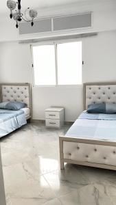 - 2 lits dans une chambre blanche avec 2 fenêtres dans l'établissement Tetouan Relax Apartement, à Tetouan