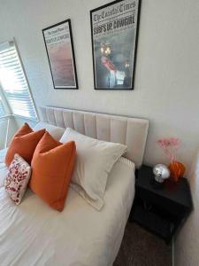 1 cama blanca con 2 almohadas y 2 cuadros en la pared en Entire Home by Newport Beach, Disneyland and SNA! en Costa Mesa