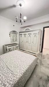 - une chambre avec un lit blanc et un lustre dans l'établissement Tetouan Relax Apartement, à Tetouan