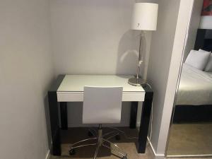 a desk with a chair and a lamp and a bed at CBD studio with balcony+pool+gym+sauna in Brisbane