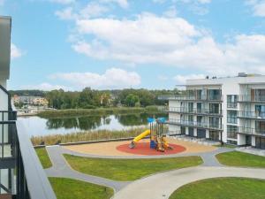 a playground in front of a building next to a lake at Apartment with beautiful view, Dziwnów in Dziwnów