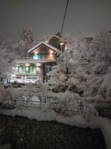 een huis bedekt met sneeuw 's nachts met lichten bij The Bungalows in Sarajevo
