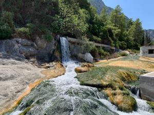 une cascade dans une rivière avec des rochers et des arbres dans l'établissement ΕΥμορφο σαν παραμύθι ΑΜΥΓΔΑΛΙΑ, à Amfikleia