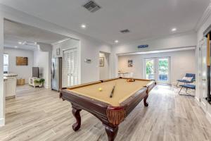 a pool table in a living room next to a kitchen at Mango Manor - Walk to Las Olas! in Fort Lauderdale
