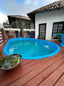 una piscina con una fuente en una terraza de madera en Pousada Aconchego do Beija Flor en Bombinhas