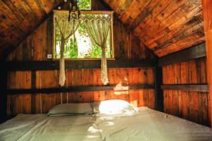 uma cama num quarto de madeira com uma janela em Fazenda Alegria Camping & Aventura no Rio de Janeiro