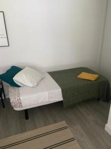a small bedroom with a bed with a green blanket at Cáscaras in Camarma de Esteruelas