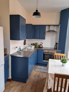 a blue kitchen with blue cabinets and a table at Beautiful Apartment in the city center in Belfast
