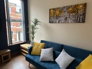 uma sala de estar com um sofá azul com almofadas amarelas em Beautiful Apartment in the city center em Belfast