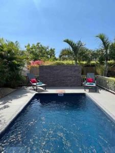 a swimming pool with two chairs in a backyard at Calme et Bien-Être « Villa Sous Le Manguier » in Rivière Noire