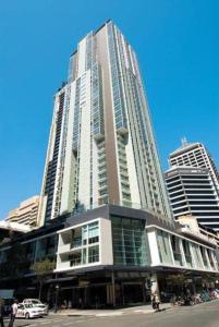 a tall building with a car parked in front of it at Prime location - CBD Brisbane 1 bed w shared 25m pool, gym, sundeck and a BBQ area in Brisbane
