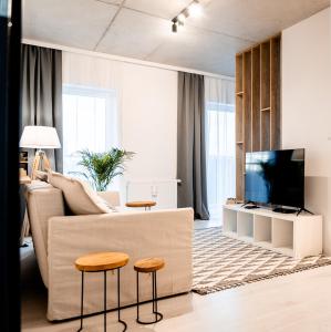 a living room with a couch and two stools at Hop & Lulu Premium Apartments in Gollnow