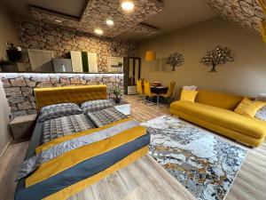 een slaapkamer met een bed en een gele bank bij Gold Downtown Apartman in Debrecen