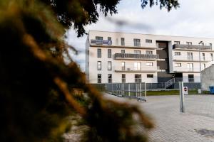 a large white building with a fence in front of it at Hop & Lulu Premium Apartments in Goleniów