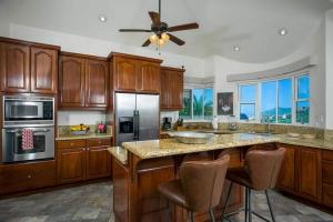 uma grande cozinha com armários de madeira e uma ventoinha de tecto em Sunset View Villa Pedregal em Cabo San Lucas