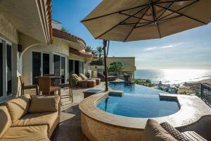 a house with a swimming pool and an umbrella at Sunset View Villa Pedregal in Cabo San Lucas