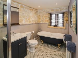 a bathroom with a tub and a toilet and a sink at Bow Cottage in Cheltenham