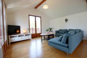 ein Wohnzimmer mit einem blauen Sofa und einem TV in der Unterkunft Le jai alai in Saint-Jean-Pied-de-Port