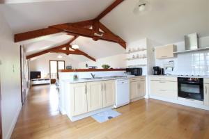 a large kitchen with white cabinets and a wooden floor at Le jai alai in Saint-Jean-Pied-de-Port +8 photos