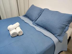 1 cama con sábanas azules y 2 toallas enrolladas en Belo Apartamento no centro de Curitiba, en Curitiba