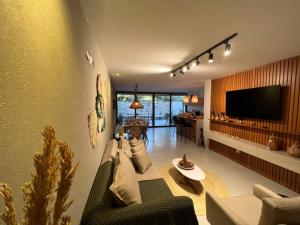 a living room with a couch and a tv at Kanui Casa Maré 107 in São Miguel dos Milagres
