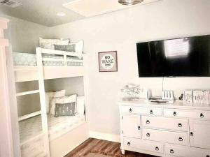a bedroom with a bunk bed and a tv and a white dresser at Fun-filled Luxury Beach Vacation Experience - Family Friendly Quiet Cul De Sac! in Bolivar Peninsula