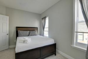 a bedroom with a bed with white sheets and two windows at Cozy Maryland Getaway in the Heart of Baltimore! in Baltimore