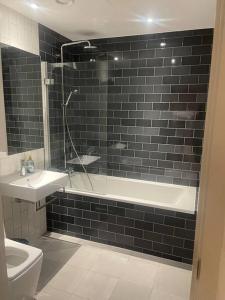 a bathroom with a tub and a sink and a toilet at Stunning 2 Bedroom Apartment in London