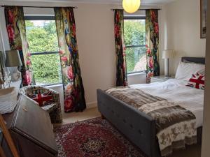 a bedroom with a bed and two windows at Panoramic sea views, sleeps 4, Torquay in Torquay