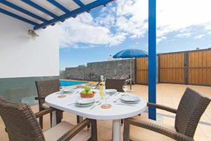 a white table with chairs and an umbrella on a patio at Villa Acomari in Playa Blanca