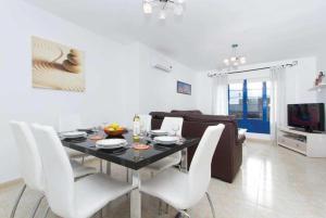 a dining room with a table and white chairs at Villa Acomari in Playa Blanca