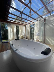 a large white tub in a bathroom with a window at Chales Labelle - 5 minutos do Centro e da Rodoviária de Santa Teresa in Santa Teresa