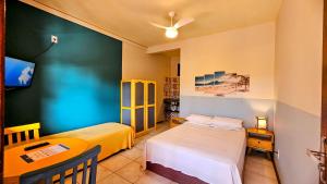 a room with two beds and a tv in it at Vila no Rosa Hospedaria in Praia do Rosa