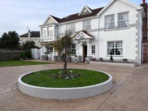 a white house with a tree in front of it at Family & friends get together birthday hot tub in Porthcawl